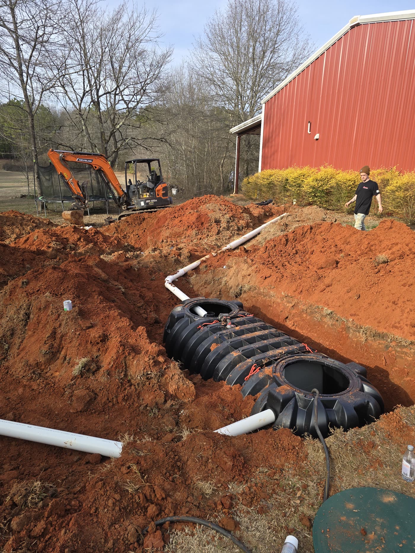 New septic tank set beside a red barn — rural North Georgia install
