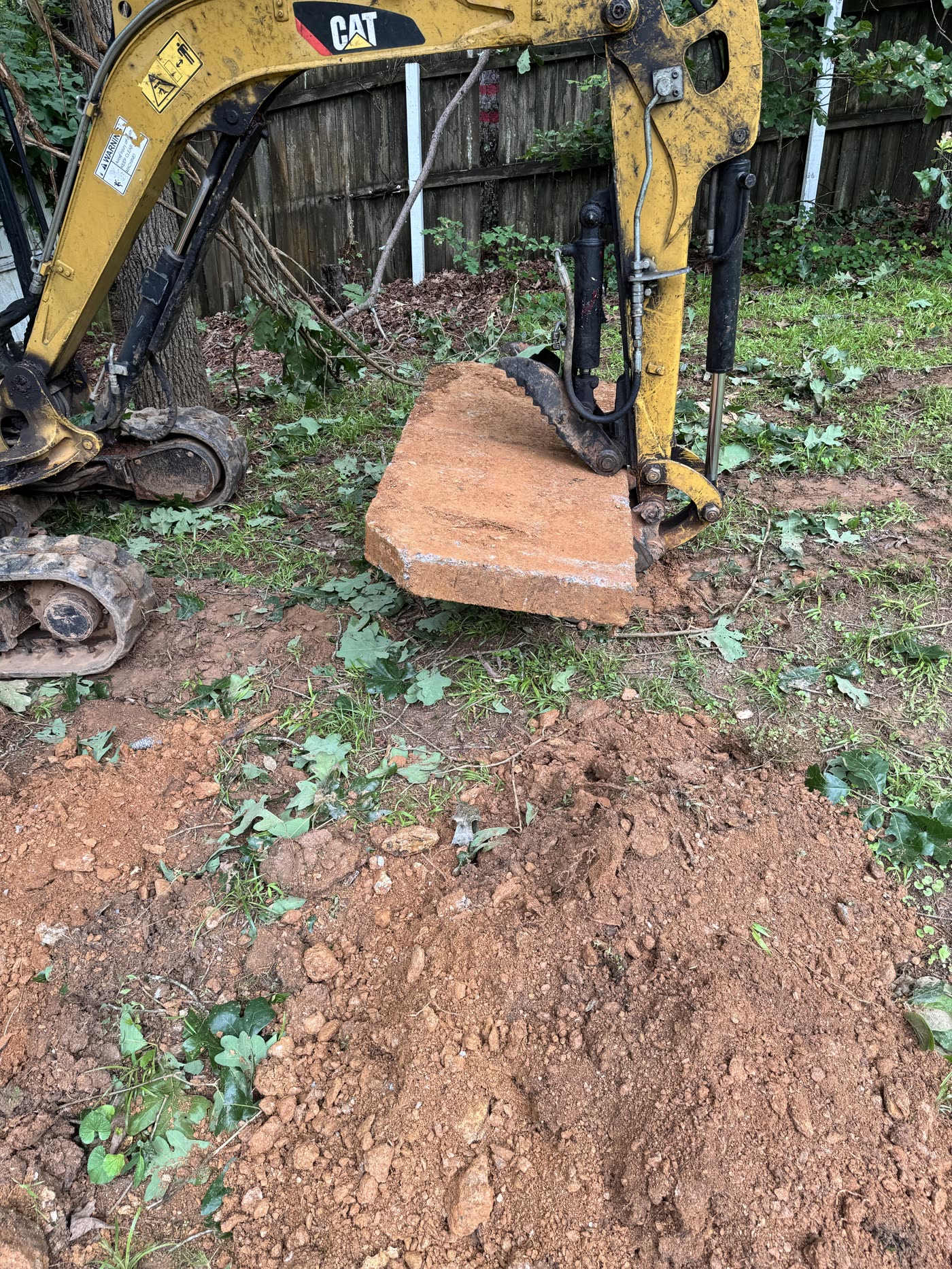 Excavator lifting the concrete lid off a septic tank