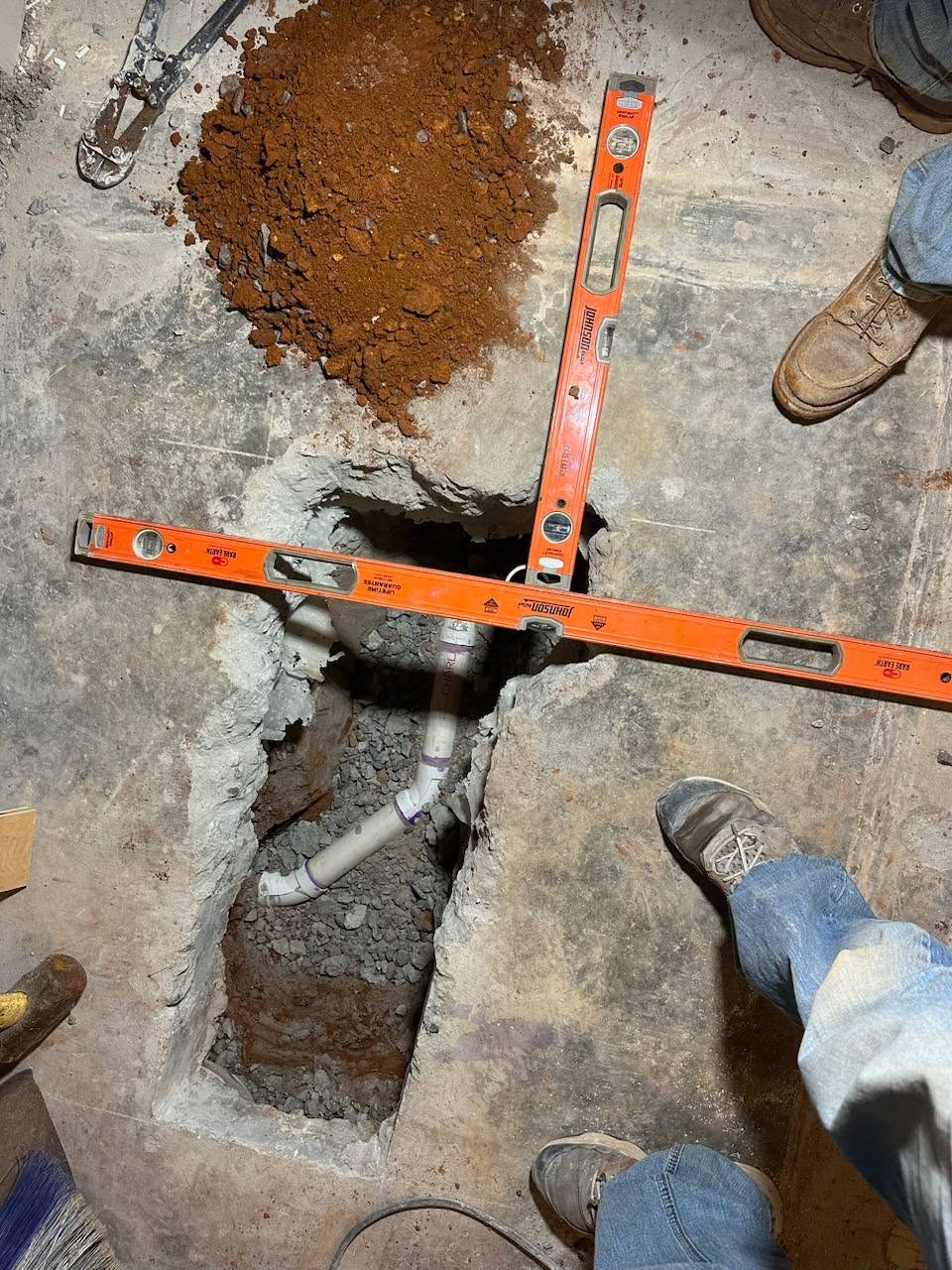Under-slab PVC drain installed in gravel with levels checking grade
