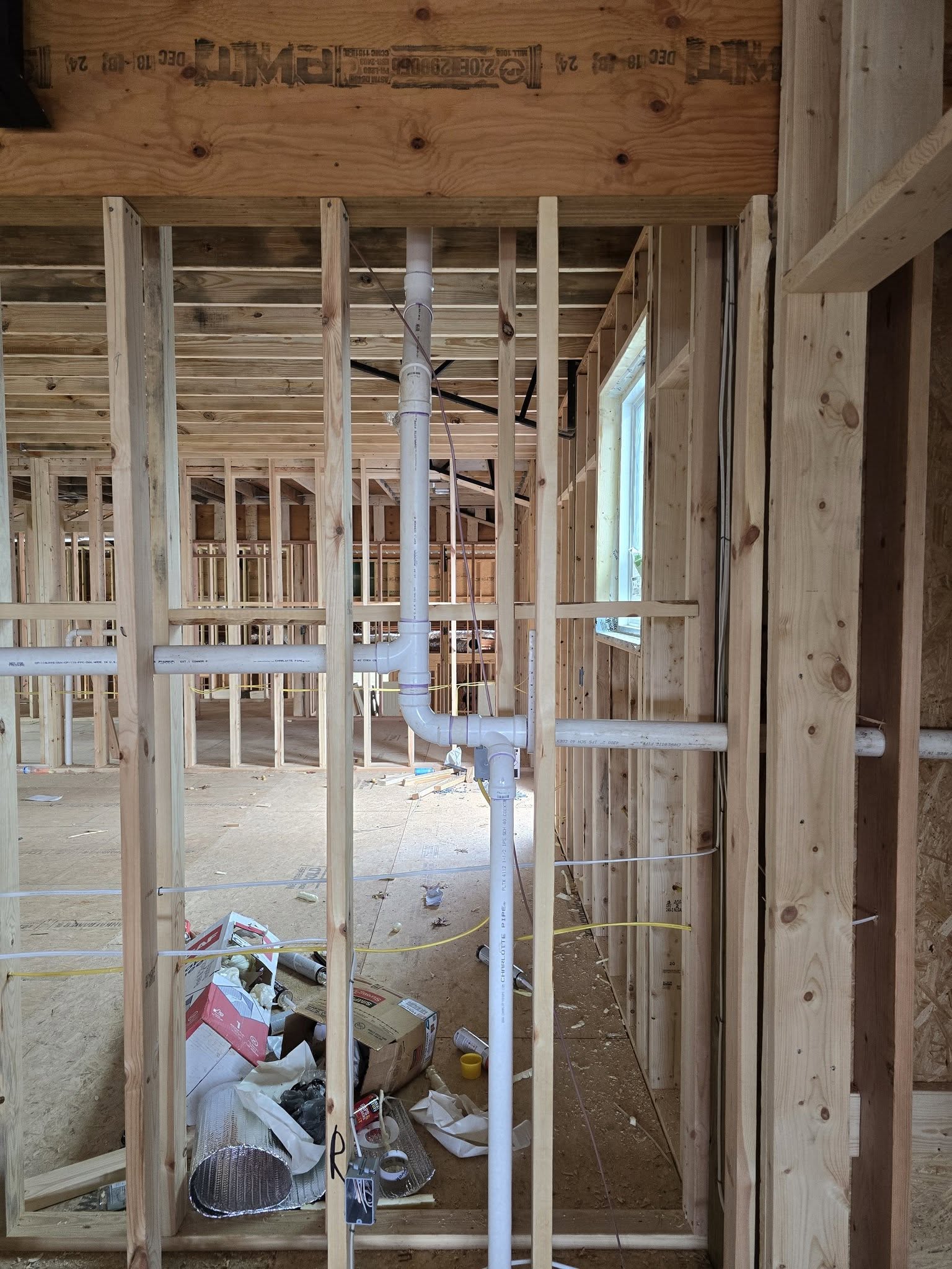 PVC drain and vent stack rough-in through wood framing on a new home