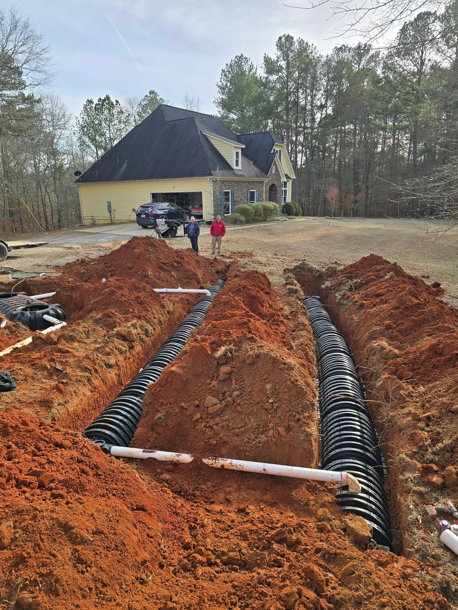 Septic drain field chambers and PVC laterals installed in red clay soil